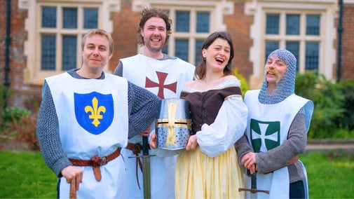 A group of four actors dressed as medieval knights stood in front of a large country house.